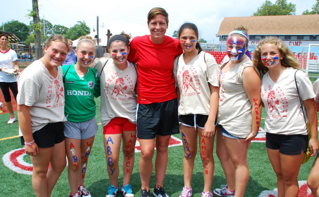 Abby Wambach group photo with girls in facepaint and Abbys name written on their legs