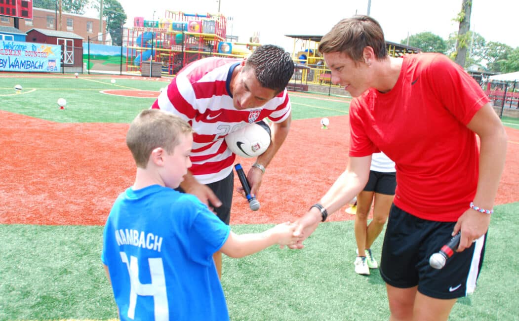 Abby Wambach shaking a young campers hand