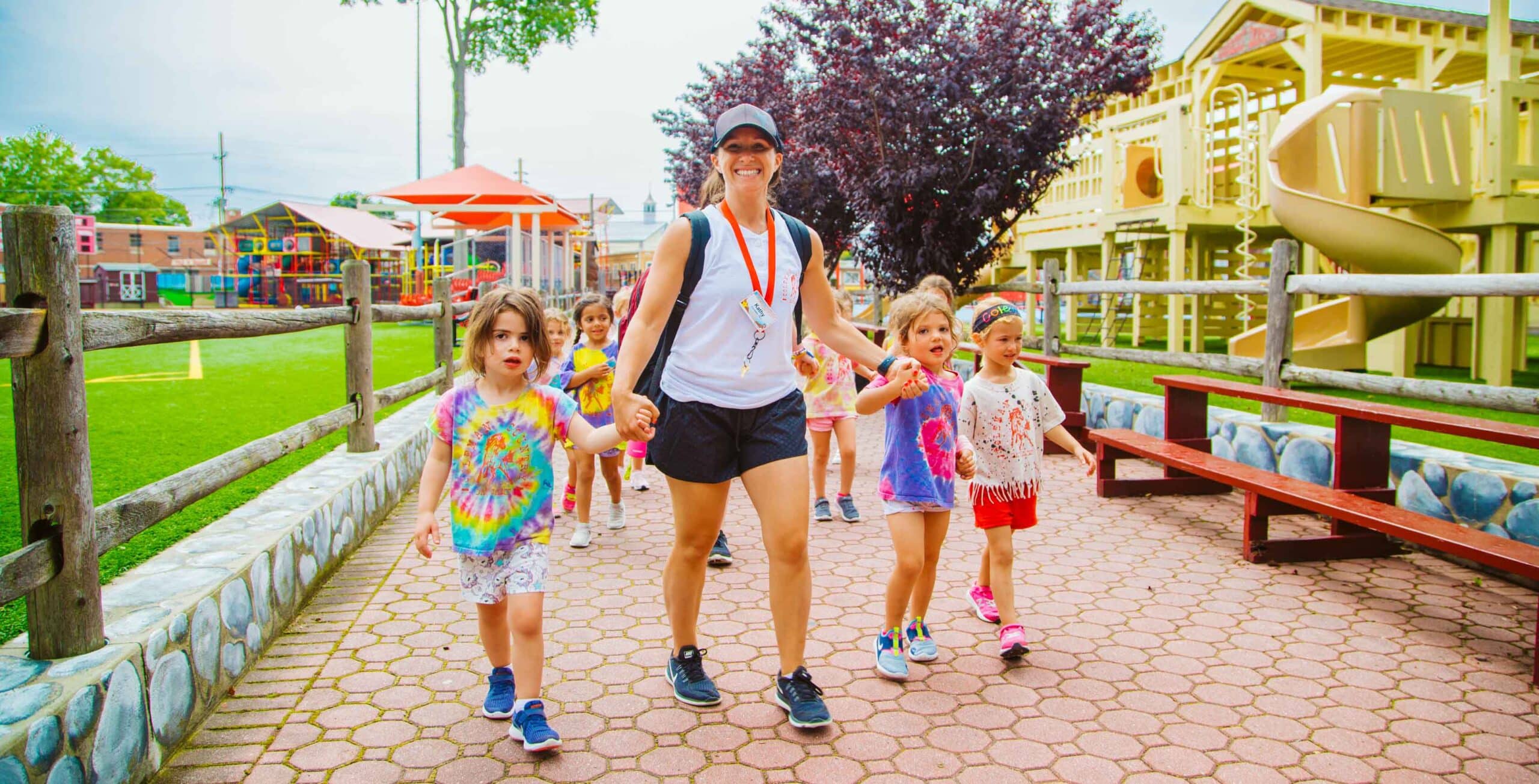 Smiling counselor walking campers on a path at camp