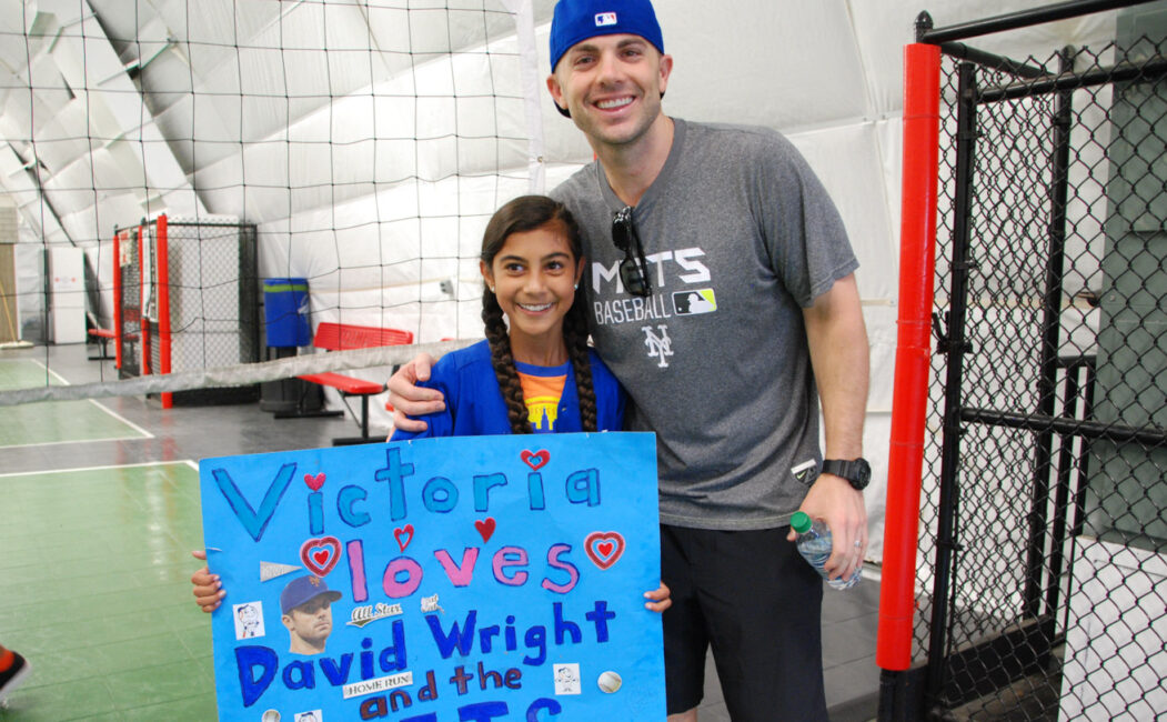 David Wright taking a photo with a camper holding a poster she made for him