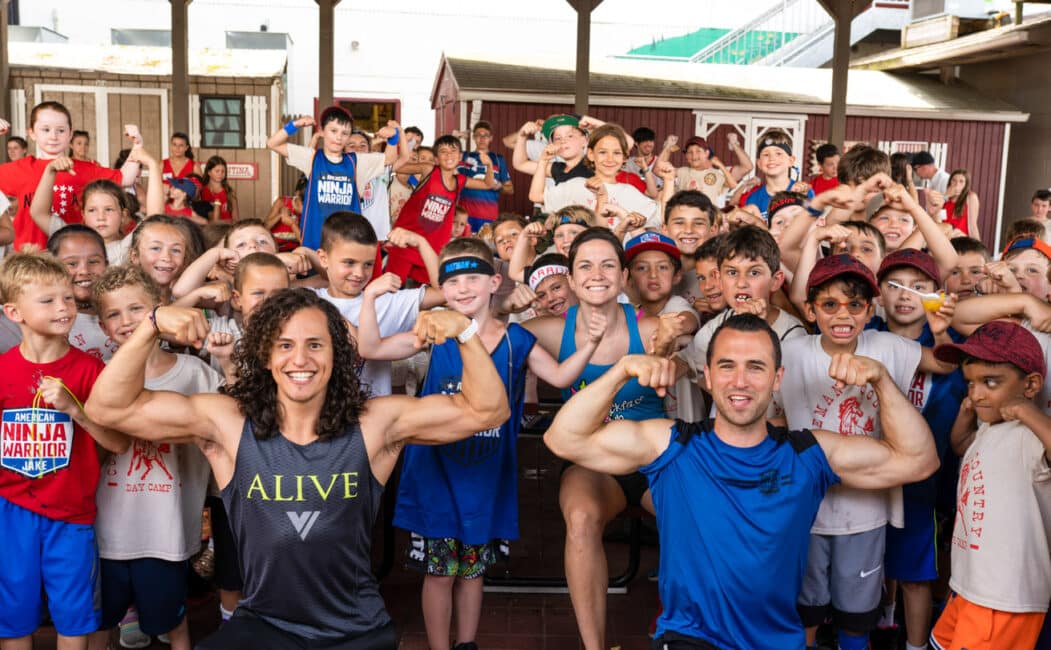 American Ninja Warrior's Daniel Gil, Joe Moravsky, and Flex Labrek wth group of campers all flexing