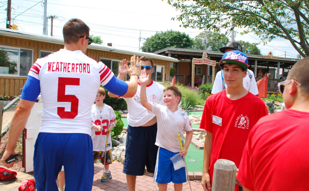 Steve Weatherford high fiving a line of campers