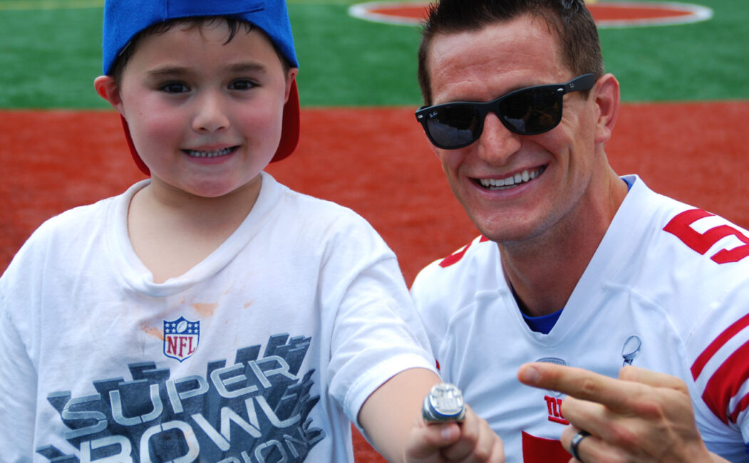 Steve Weatherford pointing to his super bowl ring worn by a young camper