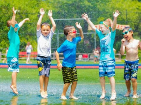 Campers jump around in water spray