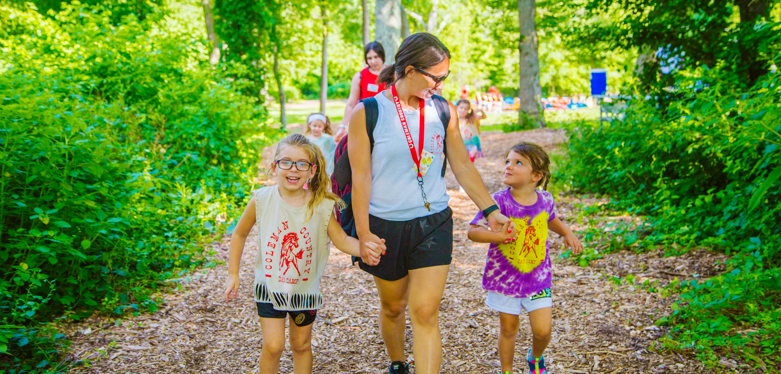 Counselor walking hand in hand with two campers.