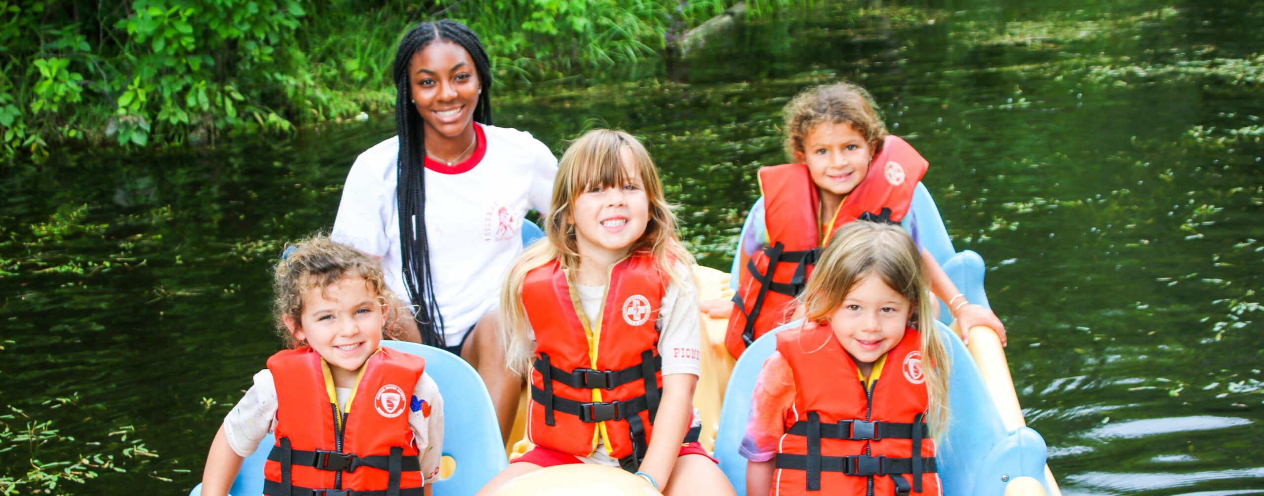 Campers and counselor with life vests on the lake.