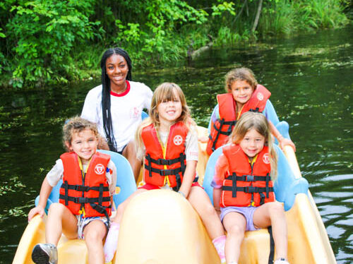 Counselor with campers on a peddle boat.