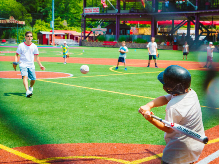 Camper hitting a baseball during a baseball game.
