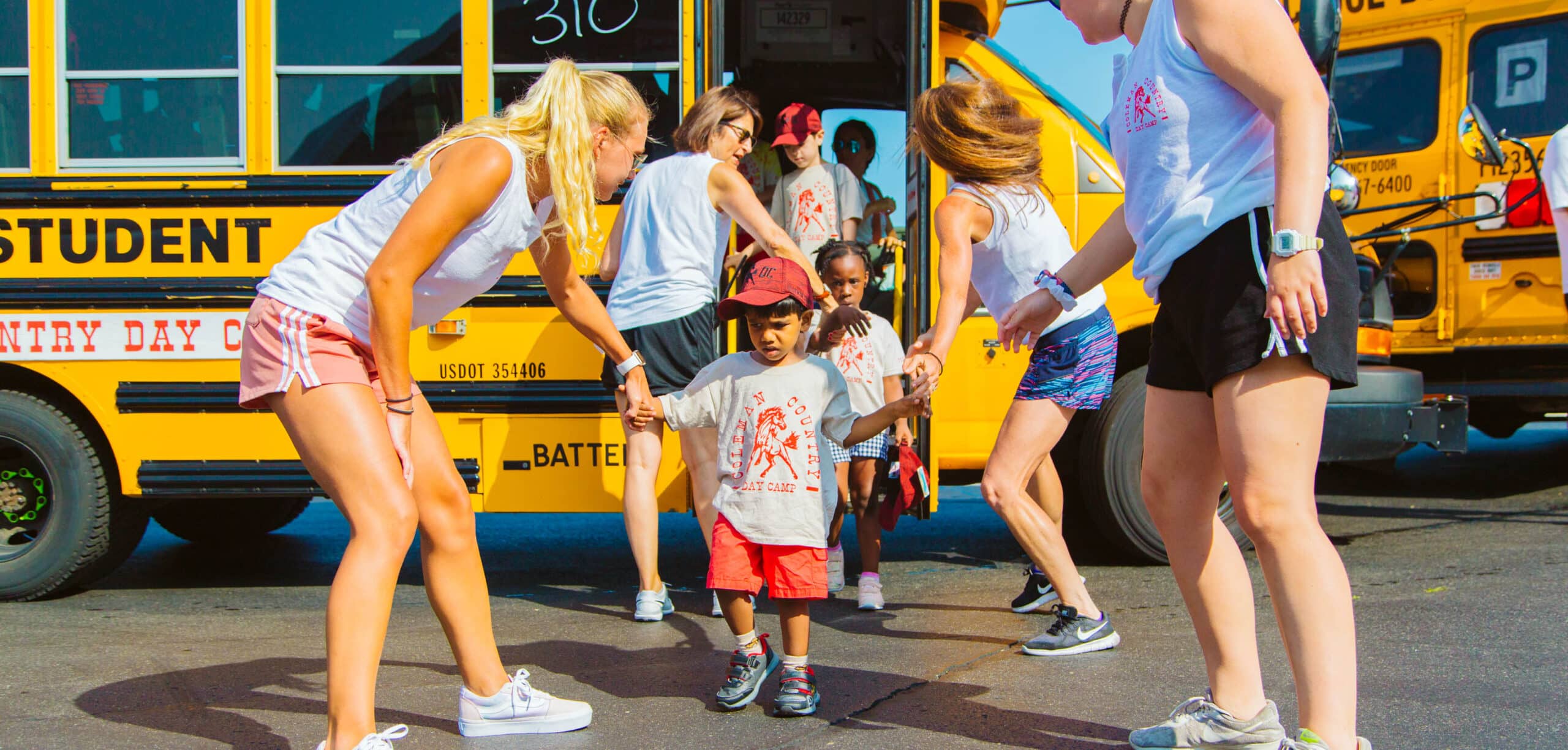 Counselor helping kids off the bus.