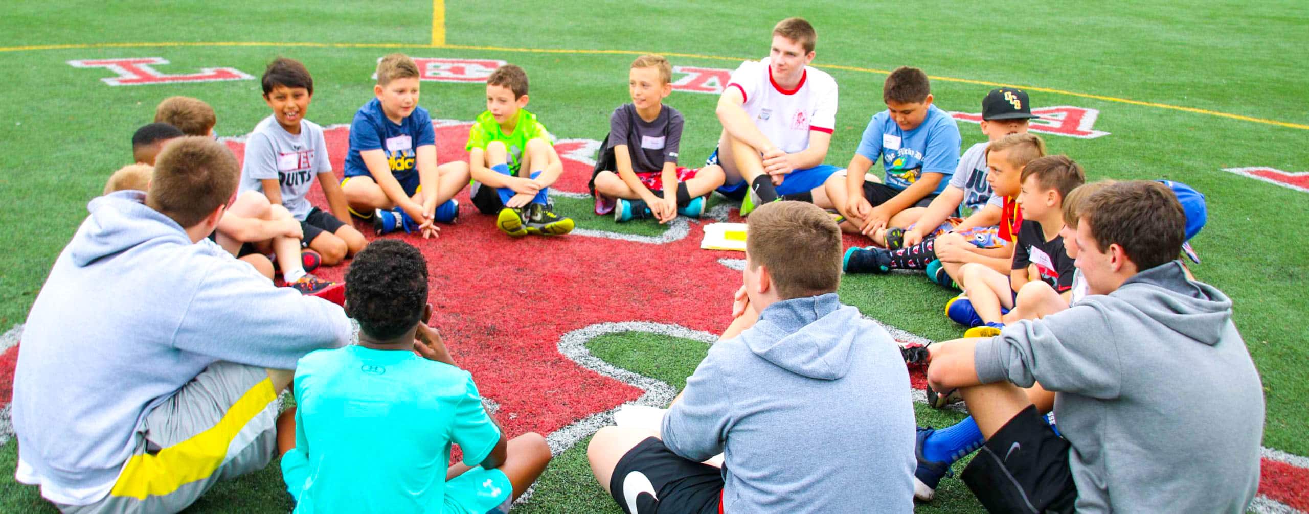 Group of kids sitting in a circle on a field