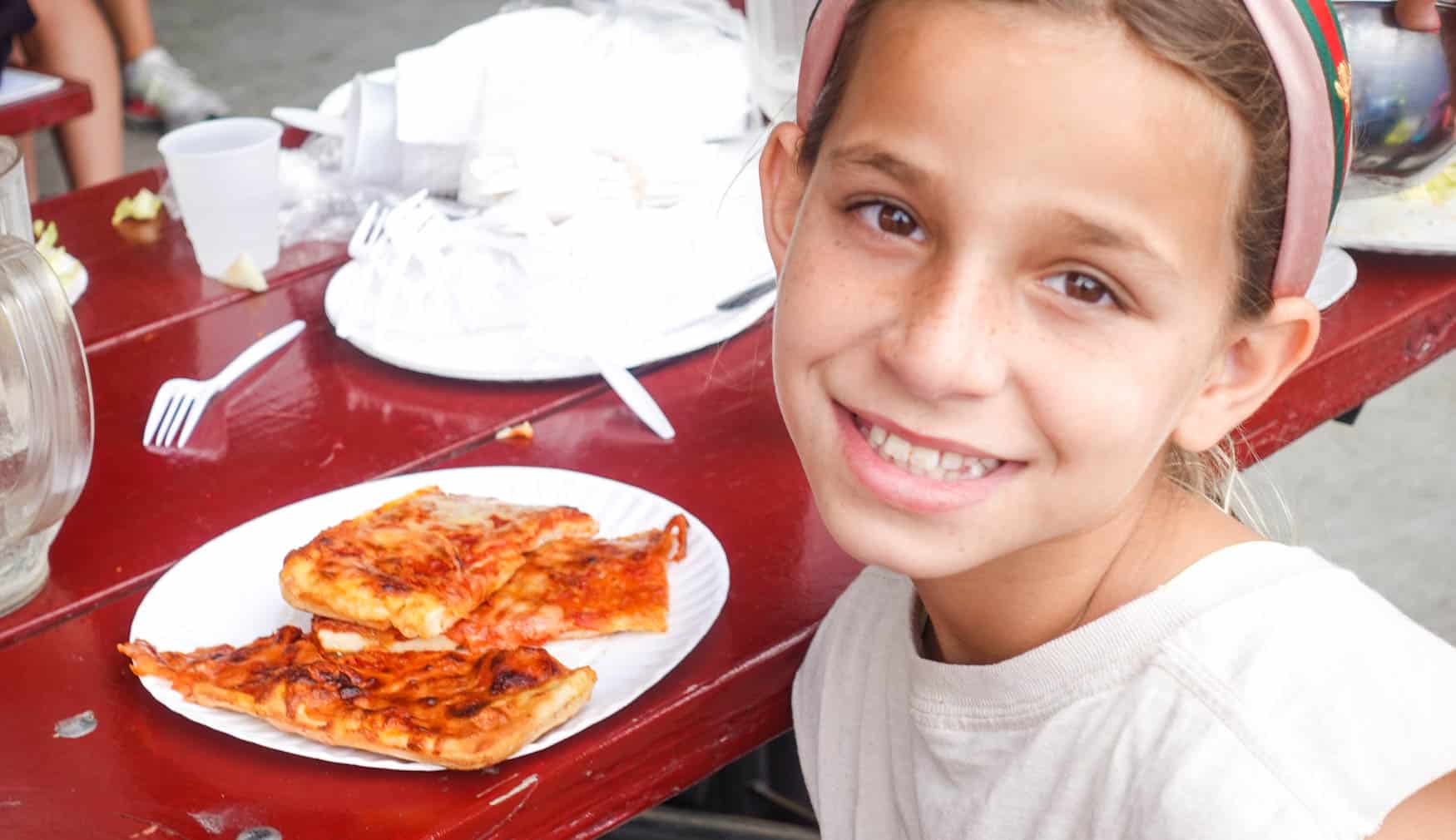 Camper smiling with a plate of pizza.