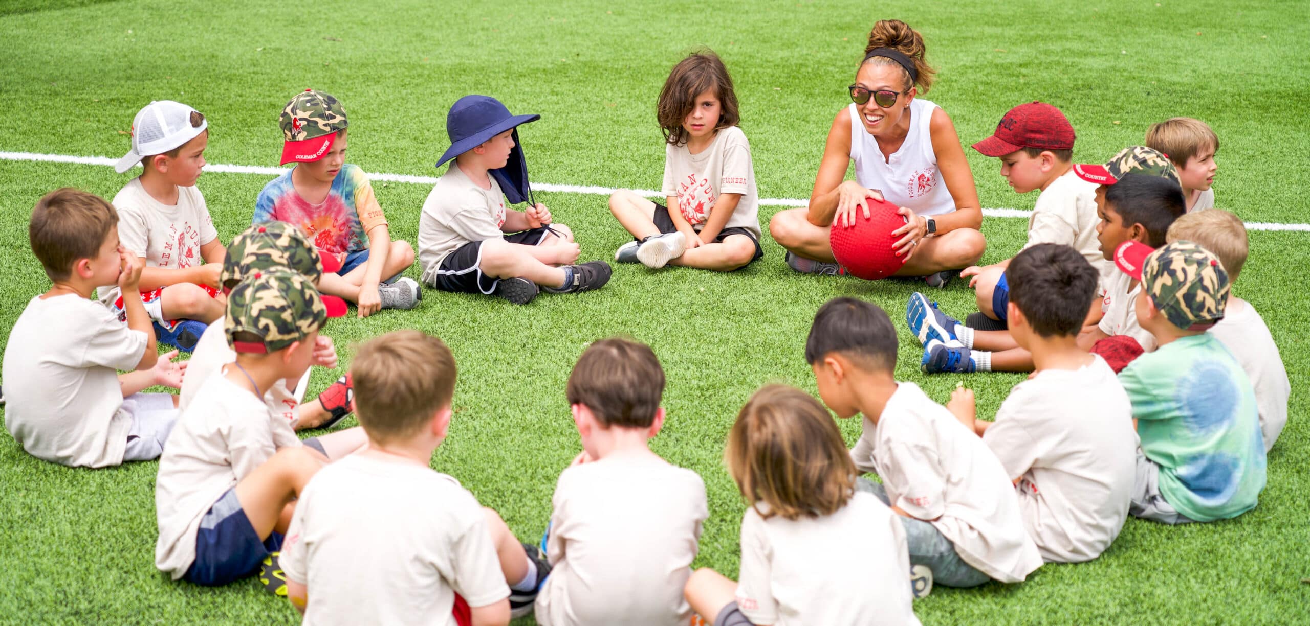 Campers sitting in a circle on the field.