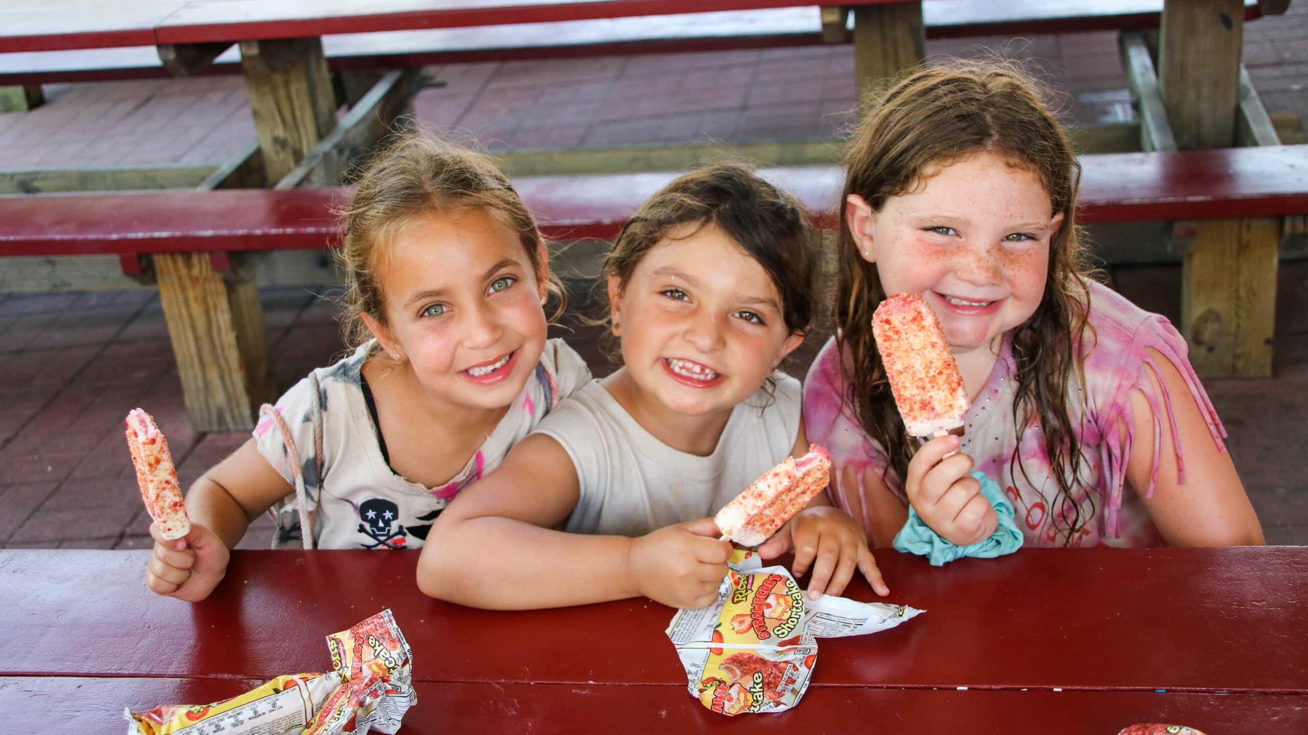 Three campers eating popsicles together.