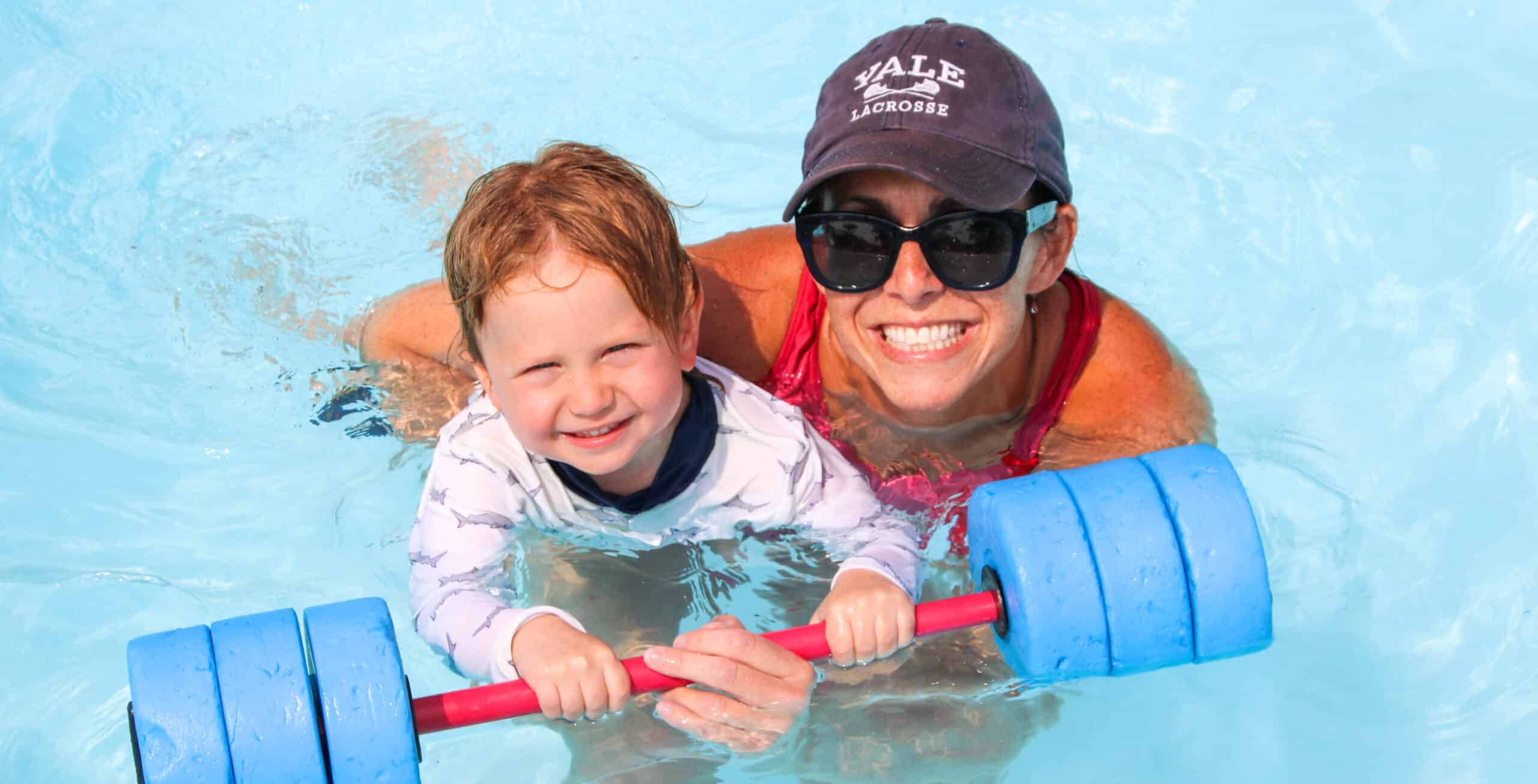 Counselor teaching a camper how to swim.