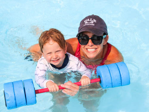 Counselor helping a camper learn to swim.