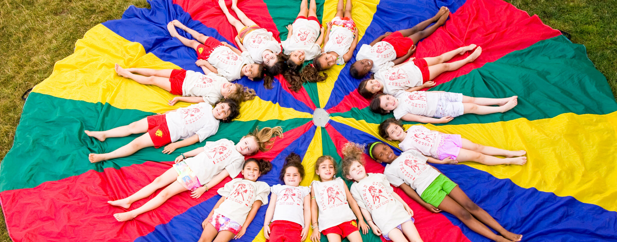 Campers laying in a circle on top of a parachute.
