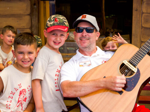 Staff member hanging out with a guitar with campers.