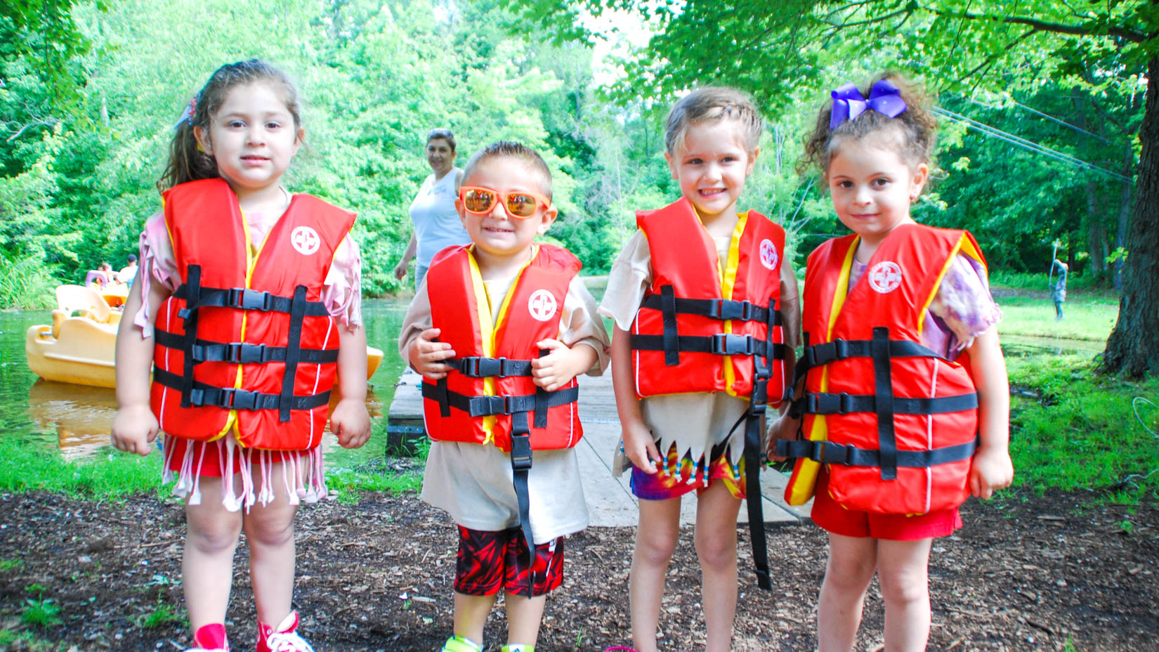 Four young campers with life vests on.